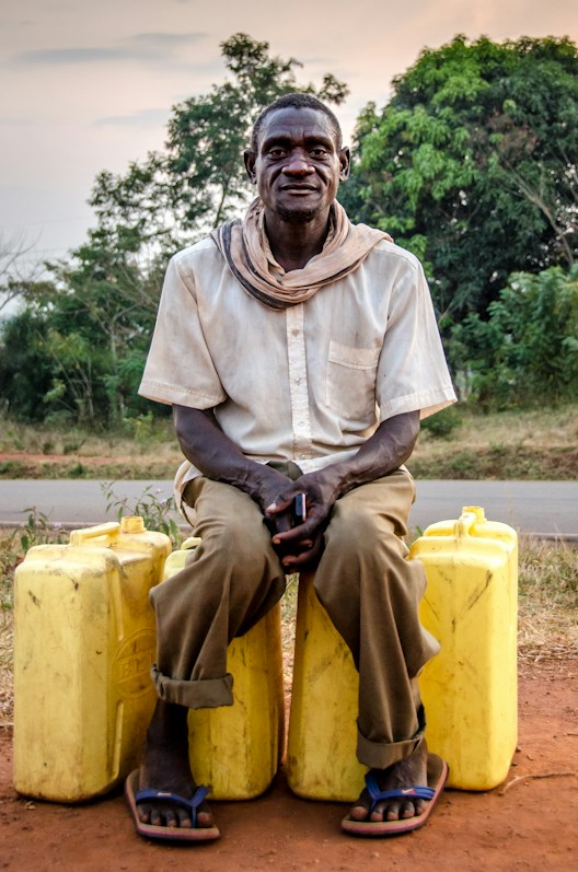 Man sitting with water cans